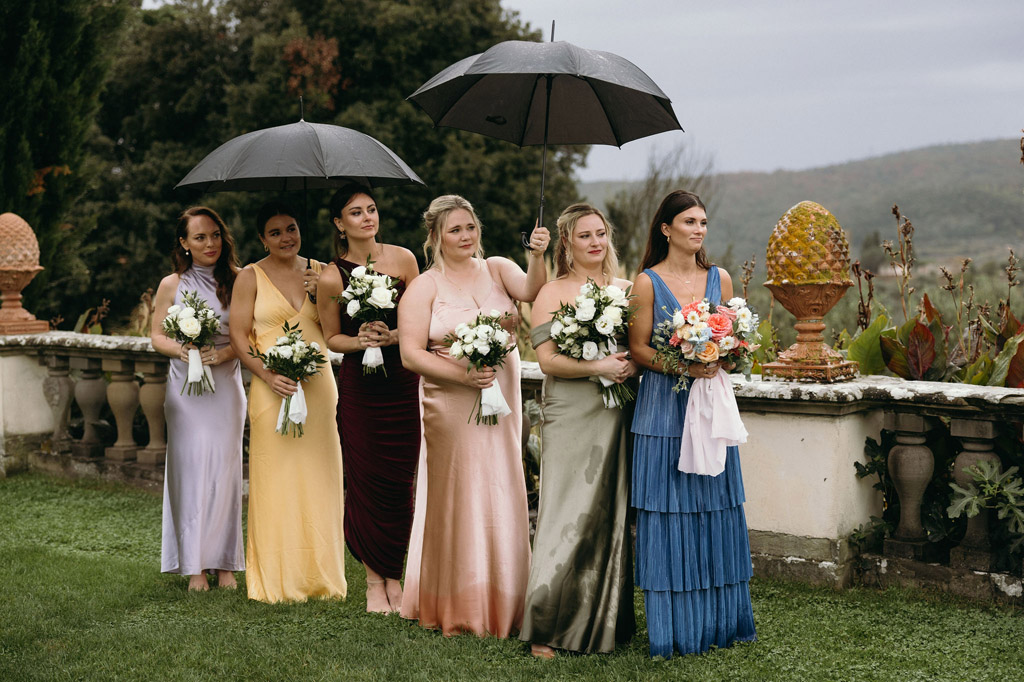 Bridesmaids standing under umbrellas at a Tenuta di Artimino wedding ceremony.
